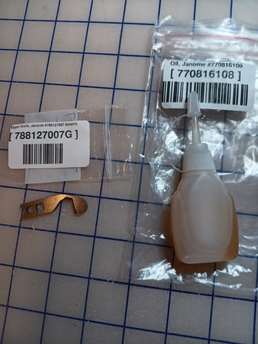 Customer's new Janome Upper Knife laid out next to its packaging and a bottle of Janome oil.