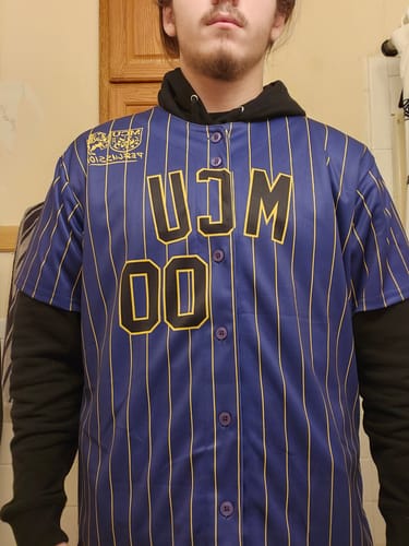 Customer wearing the front of a custom purple baseball jersey with gold pinstripes and 'MCU 00' text.