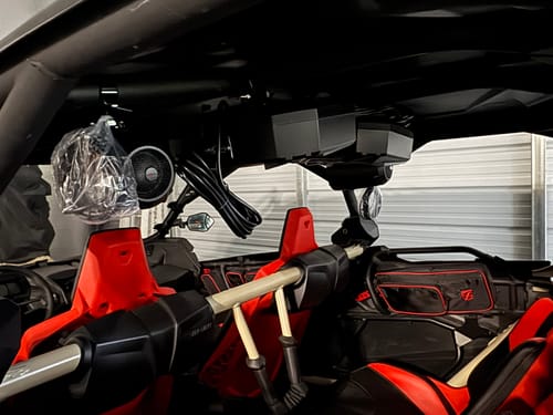 Reviewer installing a NOAM HS2 Amplifier and speaker system on the roll cage of an off-road vehicle.