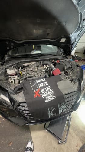 Customer's black Voided Tee laid across the open engine bay of a car.