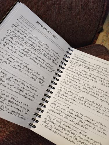 Reviewer's 2026 Dreambook + Planner open to the 'Physical Wellness' page, filled with handwritten notes.