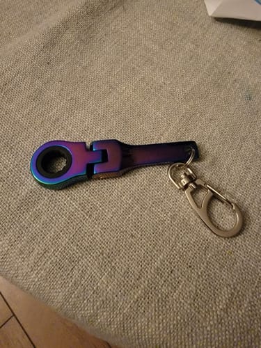 Reviewer's iridescent 10mm Wrench Keychain resting on a gray fabric surface.
