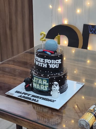 Customer's black two-tier Star Wars Tier Cake decorated with character figures and '21' birthday candles.