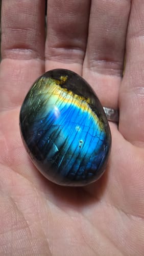 Reviewer holds their Labradorite crystal in hand, showing vibrant blue and yellow colors in the light.