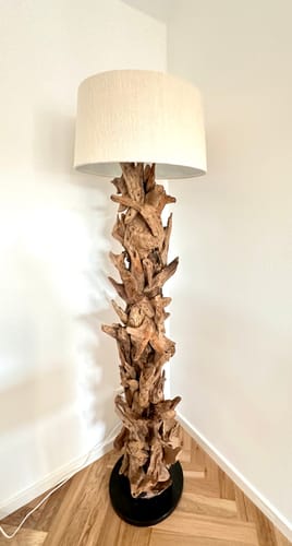 Ein Rezensent zeigt die Stehlampe Treibholz CLEON. Die hohe Lampe mit Treibholzfuß und beigem Schirm steht in einer Raumecke.