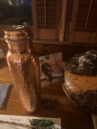 Customer's Himalayan Ayurvedic Pure Copper Bottle with a hammered finish, displayed on a wooden surface.