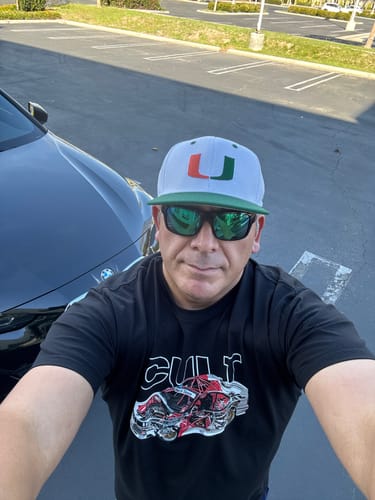 Customer wearing the black G82 TRIPLE TEE with a car graphic, standing outdoors.