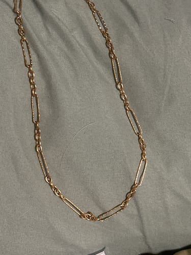 A customer's gold Dubai Hills Necklace laid out, showing the textured elongated links of the chain.