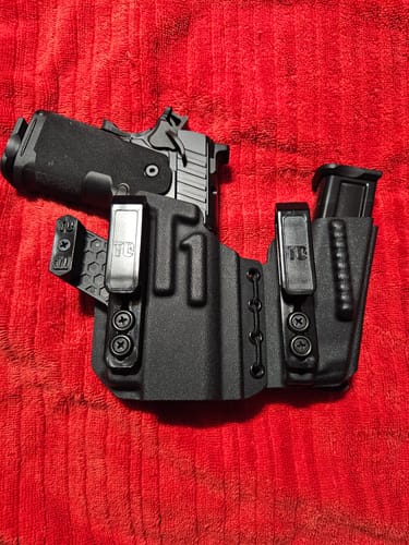 Customer's black AXIS ELITE holster holding a handgun and a spare magazine on a red textured surface.