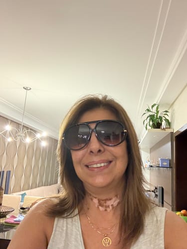 Cliente sorrindo em uma selfie, usando os grandes óculos de sol Veneza.