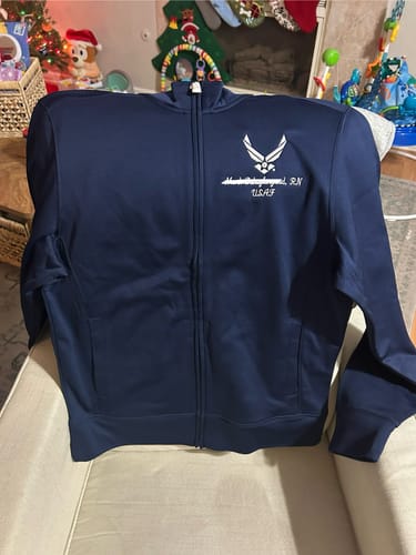 Reviewer's personalized navy Sport-Wick® full-zip jacket with custom embroidery, draped over a chair.