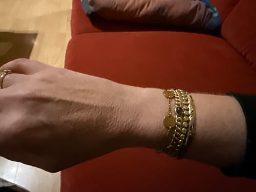 Customer wearing the shiny Classic Bezel Tennis Bracelet stacked with other gold-colored bracelets on their wrist.