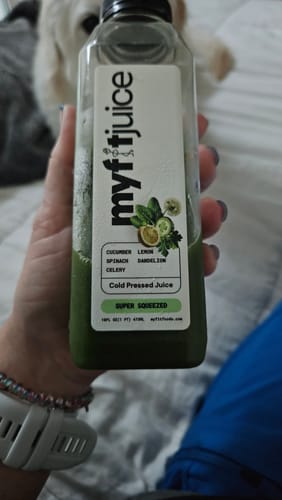 Customer holding a bottle of the Super Squeezed green juice by My Fit Juice, showing the label.