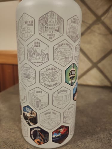 Reviewer's Canada Bottle showing the engraved map with a few colorful destination stickers applied to their corresponding hexagons.