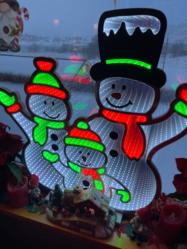 Kundens LED-lysskilt med snømenn som viser en fin speileffekt i et vindu.