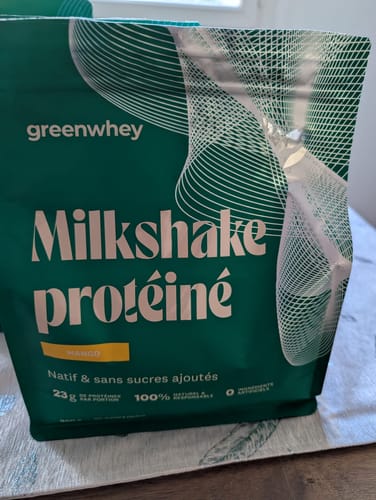 Gros plan par un client du sachet de Milkshake protéiné vert à la saveur mangue.