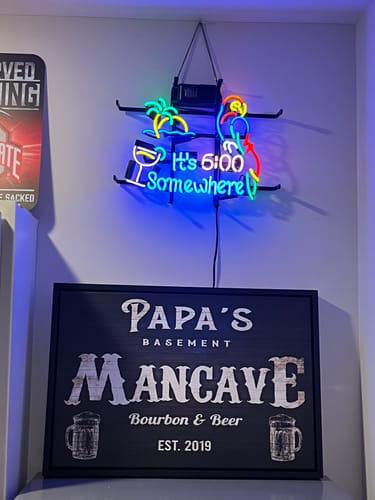 Customer's custom Neighborhood Tavern Sign for 'Papa's Basement Mancave,' shown hanging on a home wall.