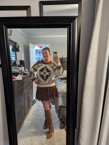 Reviewer in a mirror selfie wearing the Lean On Me Aztec Long Sleeve Knit Sweater with a skirt and boots.