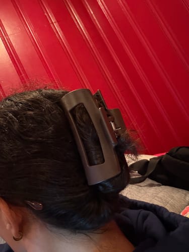 Close-up of a reviewer wearing a dark cloud clip holding up their dark hair.