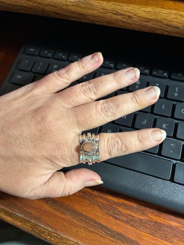 Reviewer's hand wearing the wide Peach Moonstone Celestial Fidget Ring over a keyboard.