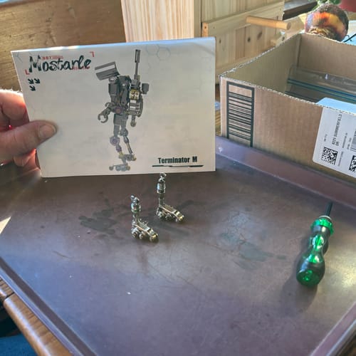 Customer holding the Terminator M manual with two assembled mechanical legs on a tray.