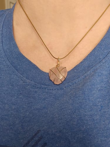 Customer wearing a heart-shaped Rose Quartz necklace with a gold-colored wire wrap and chain.