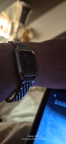 Close-up of a reviewer wearing the elegant CLAIRE DE MAINS watch on their wrist in a dimly lit setting.