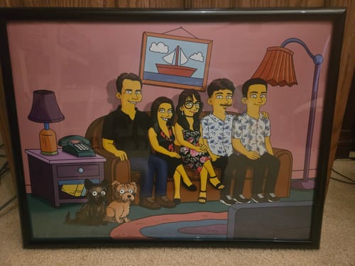 Customer's horizontal poster showing a custom cartoon illustration of their family and two puppies, displayed in a black frame.