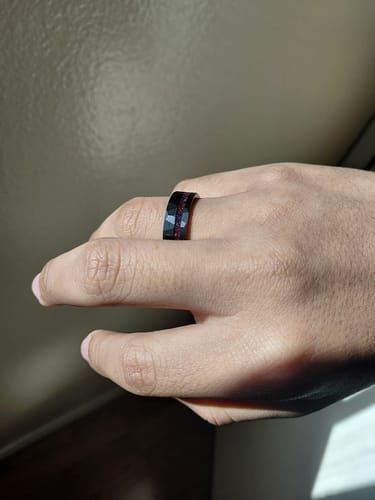 Customer wearing the black Krysen ring, showing the hammered finish and red opal inlay on their finger.