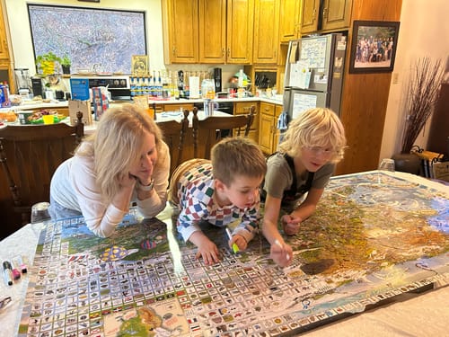Customer and two children gathered around a table, enjoying the large World's Greatest Search & Discover poster.