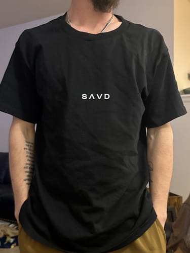 Reviewer wearing the black John 3:16 Oversized T-Shirt, showing the front 'SAVD' logo.