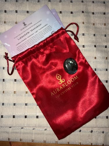 Reviewer's monthly crystal delivery: a Labradorite Moonstone, red pouch, and informational cards from the VIP Crystal Club.