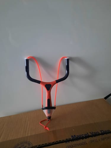 Recensent toont de oranje en zwarte MATCHPULT katapult die op een doos staat.