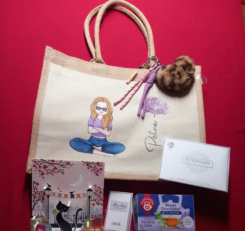 Kunde zeigt seine personalisierte Jute-Tasche mit einer Illustration einer Frau und dem Namen 'Petra', arrangiert mit anderen Artikeln.