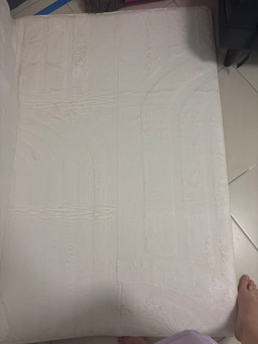 Customer's soft, light-colored Mellow Mat laid out on a tiled floor, showing creases from shipping.