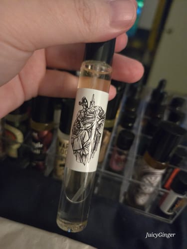Customer holding a clear rollerball bottle of the Cold Heart fragrance in their hand.