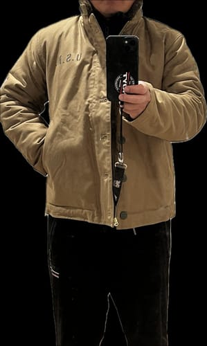 Reviewer's mirror selfie showing the fit of their size 40 khaki N-1 Deck Jacket with the collar up and hands in the pockets.