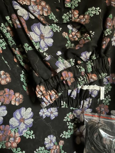 Customer's close-up of the artsy flower denim pants, showing the detailed floral pattern and elastic ankle cuff.