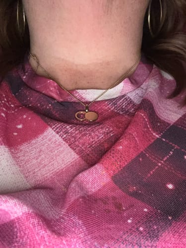 Close-up of a reviewer wearing the large gold 'The Empty Tomb' pendant necklace against their chest.