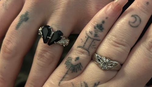 Close-up of a reviewer's tattooed hand wearing the PROMISE RING with two black coffin-shaped stones.