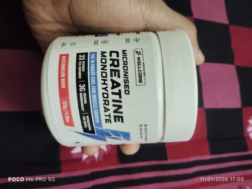 Customer holding a white tub of Wellcore Micronised Creatine Monohydrate in the Watermelon Wave flavor.