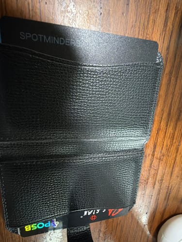 Customer's SPOTMINDERS Tracking Card partially inserted into a black textured wallet.
