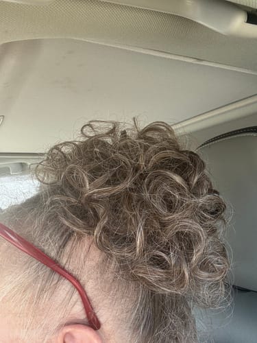 Reviewer showing a close-up of their JuvaBun Curled Clip-in Bun in a mixed brown and grey color.