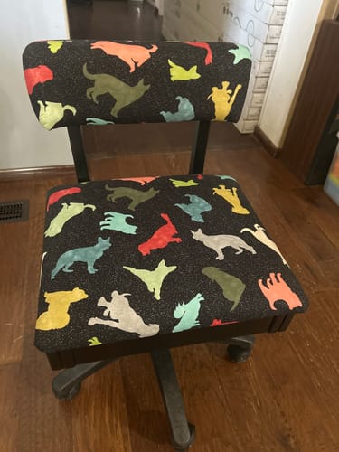 Reviewer's Arrow Hydraulic Sewing Chair with a colorful dog-pattern fabric, shown on a hardwood floor.