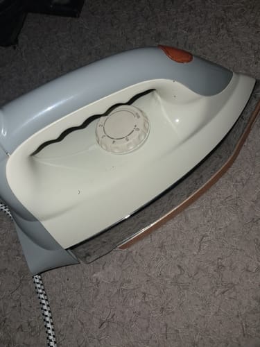 Customer's grey and white Geepas Automatic Dry Iron resting on a carpet, showing the temperature dial.