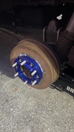 Close-up of a customer's blue hubcentric wheel spacer installed on a rusty wheel hub before wheel installation.