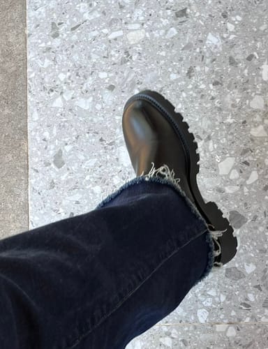 תקריב של לקוחה הנועלת מגף Kenova שחור עם ג'ינס כהה.