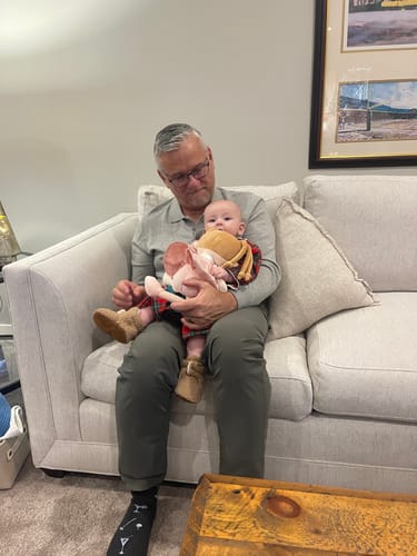 Customer shows a baby cuddling the soft Personalized Sweetheart Girl doll while being held by a person on a couch.