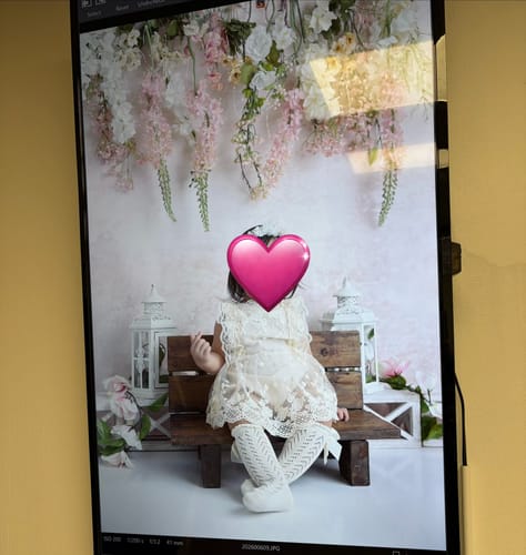 A customer's baby wearing the Everly Lace Romper in Ivory while sitting on a bench during a photoshoot.