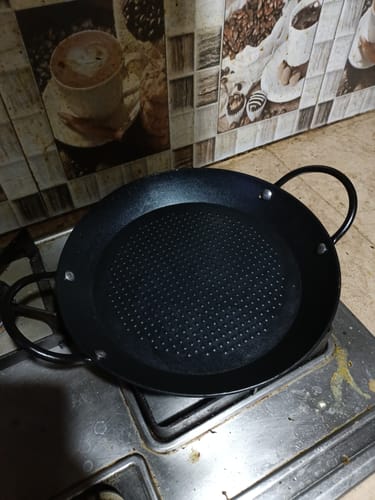 Customer's black Non-Stick Pan with a textured surface resting on a gas stovetop.